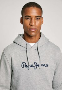 Grijze hoodie van een katoenmix, met een marineblauwe geborduurde logo "Pepe Jeans" op de borst, voorzien van een capuchon met trekkoord en een kangoeroezak.