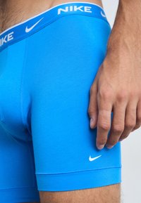 Blue Nike boxer briefs with a white waistband featuring “NIKE” lettering and logo. Material appears smooth with a close fit design.