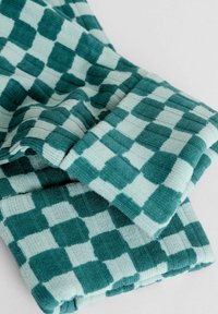 Turkoois en lichtblauw geruit stof met ribbelstructuur, gevouwen om het ontwerp en de dikte te tonen. Geen zichtbare logo's of accenten.