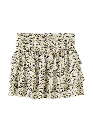 Vrouw draagt beige gehaakte haltertop, patroonlaag mini-rok en bruine gespen met studs sandaal, staand tegen een effen witte achtergrond.