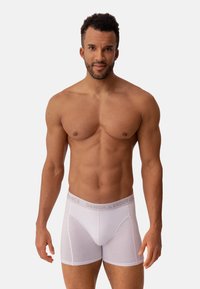 Boxer briefs blancos fabricados con un tejido ligero, que cuentan con una cinturilla elástica gris con el texto "DANISH ENDURANCE". Textura suave y diseño ajustado.