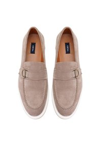 Hellebeige Wildleder-Loafers mit runder Zehenform, ausgestattet mit einem dekorativen Riemen und einer goldfarbenen Schnalle, auf einer weißen Gummisohle.