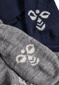 Två par strumpor i grått och marinblått, med ett vitt blommönster. Materialet är stickat med en mjuk textur.