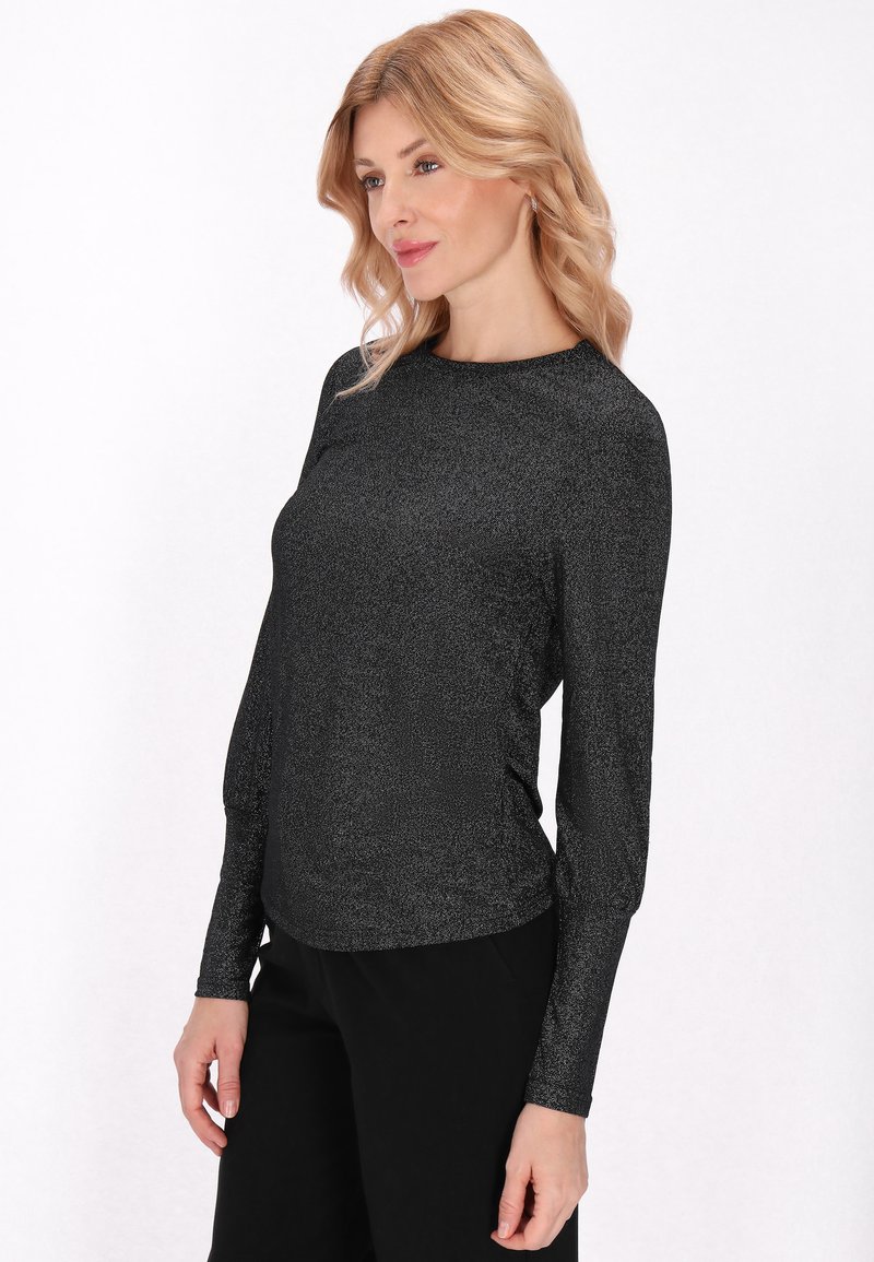 Fekete, hosszú ujjú felső fényes kötött textúrával, kerek nyakkivágással és karcsú szabással, fekete nadrággal párosítva.