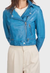 Chaqueta de motorista de cuero azul con cremalleras plateadas, un cuello estructurado y un diseño corto, que presenta dos bolsillos laterales con cremallera y un acabado texturizado.