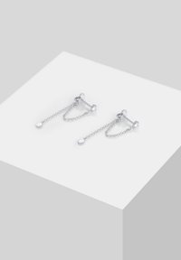 Pendientes de plata que presentan acentos en cadena, formas geométricas y detalles circulares. El diseño combina metal pulido con enlaces intrincados.