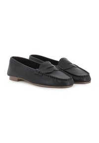 Mocasines de cuero negro con puntera redonda, que presentan un lazo decorativo y detalles de costura. Suela plana y textura suave.