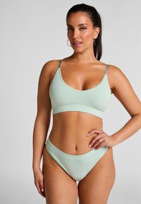 Muntgroene geribbelde bikini-set met een bralettetop met verstelbare straps en een high-waisted onderkant. Glad textuur en minimalistisch ontwerp.
