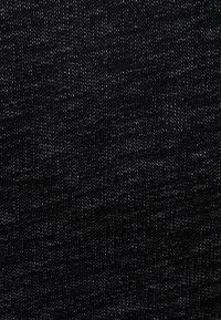 Tissu noir texturé présentant un subtil mélange de fils gris foncé et noirs, créant un motif moucheté sur la surface.