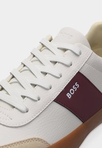 Λευκό δερμάτινο αθλητικό παπούτσι με λευκά κορδόνια, μπεζ σουέντ μύτη, μαρον πλευρικό πάνελ και λογότυπο "BOSS" στο πλάι.