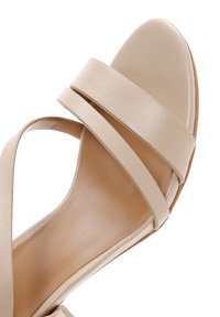 Nude-colored sandal with a smooth leather upper, featuring two wide straps across the foot and a pointed toe design. Flat sole.