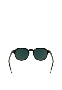 Sonnenbrille mit einem Schildpatt- Kunststoffrahmen, ovalen Gläsern und dunkelgrün getönten Gläsern. Schlanke, klare Bügel mit einer leichten Kurve.