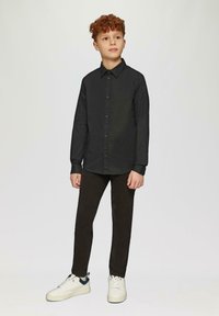 Zwart overhemden met kraag, gedragen met donkere broek en witte sneakers. Het overhemd heeft een gladde textuur en een slim-fit ontwerp.