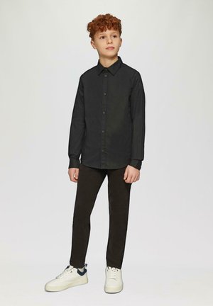 Zwart overhemden met kraag, gedragen met donkere broek en witte sneakers. Het overhemd heeft een gladde textuur en een slim-fit ontwerp.