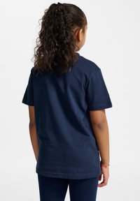 Granatowa bawełniana koszulka z standardowym krojem, krótkimi rękawami i prostym wzorem bez nadruków lub grafik, widziana z tyłu.