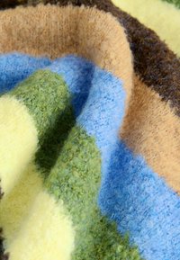 Multifarvet tæppe med tyk, blød tekstur og striber i grøn, blå, beige, brun og gul. Hygge og fyldigt materiale.