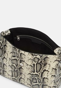 Grand sac à main en imitation serpent noir et blanc. Présente une texture lisse, une ouverture en haut, et une poche zippée intérieure pour un stockage sécurisé.