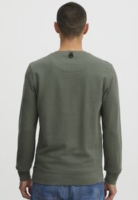 Dark green sweatshirt with long sleeves, a rounded neckline, and textured fabric. Features a rear loop detail at the neck. Casual fit.