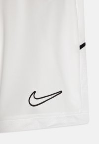 Hvite idrettsshorts laget av lett stoff med mesh-struktur, med en svart Nike-logo brodert nær kanten og en svart akcentstripe.