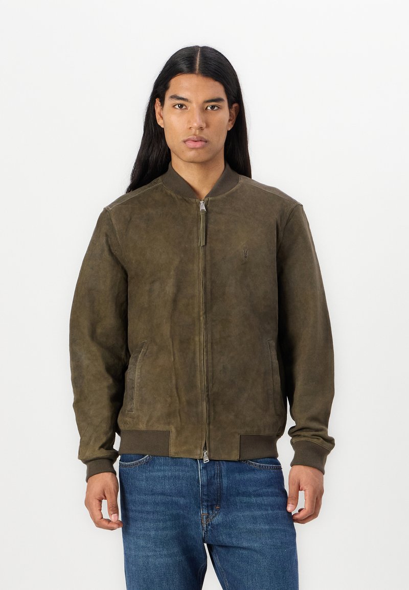 Giubbotto bomber in suede marrone con zip frontale, polsini e orlo a costine, e due tasche laterali. Presenta un logo sottile sul petto.