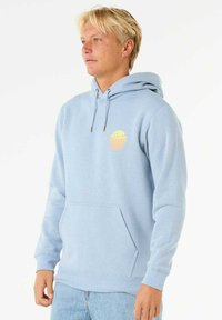 Felpa leggera blu chiaro realizzata in tessuto morbido, con tasca frontale, cappuccio con coulisse e una grafica circolare arancione sul petto.