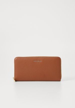 Brown leather wallet with a textured finish, gold-tone branding, zip closure, and a slim rectangular shape. No visible patterns or accents.