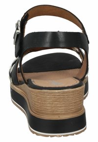 Sandale en cuir noir vue arrière avec sangle ajustable, semelle intérieure en cuir texturé marron et semelle plateforme avec une accent beige et blanche.