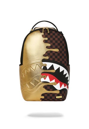 Zaino con design metà metallizzato oro e metà a scacchiera marrone, con una bocca di squalo stilizzata con denti affilati bianchi e rossi.