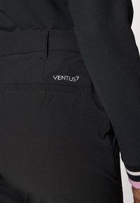 Juodos VENTUS7 kelnės su užpakaline kišenė su plokščiu uždarymu, sklandžia tekstūra ir švariomis linijomis. Nematomos raštų ar aparatūros akcentų.