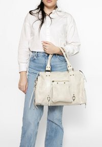 Sac à main en simili cuir blanc avec doubles poignées, plusieurs poches et accents en métal doré, doté d'une surface texturée.