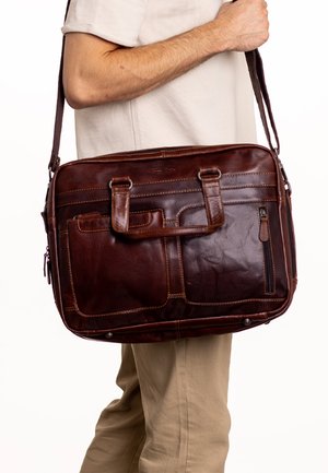 Brown leather messenger bag with dual top handles and a long shoulder strap. Features multiple pockets and stitching accents. Smooth texture.