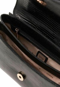 Czarna torebka ze skóry o fakturowanej powierzchni z zapięciem na zatrzask w kolorze złotym. Wnętrze wyłożone beżową podszewką, wyposażone w wiele przegródek oraz kieszeń na zamek.