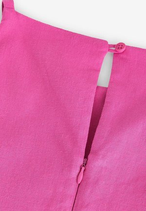 Detalj ružičastog platnenog odjevnog predmeta s malim gumbom i zatvaračem s odgovarajućom kvačicom, prikazujući teksturiranu završnu obradu.