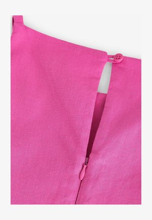 Détail d'un vêtement en lin rose présentant un petit bouton et une fermeture éclair avec un tirant assorti, mettant en valeur une finition texturée.
