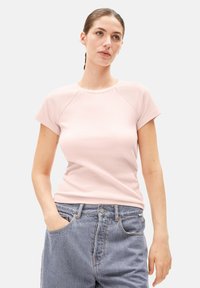 Roze geribde t-shirt met korte mouwen, een ronde halslijn en raglanmouwen, gecombineerd met lichtblauwe high-waisted jeans.