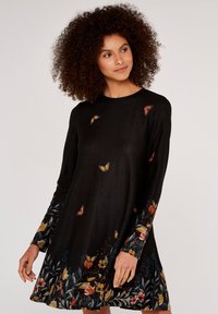 Svart långärmad klänning med flerfärgade blommor och fjärilsbroderier, med en utsvängd form och mjuk textilstruktur.