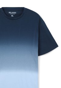 T-shirt dal taglio ampio in blu scuro che sfuma in blu chiaro. Maniche corte, collo a giro, realizzato in tessuto di cotone dalla trama liscia.