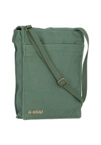 Zelená látková taška přes rameno z materiálu G-1000 s nastavitelným popruhem, obdélníkového tvaru, s přední kapsou a zlatým logem ve spodní pravé části.