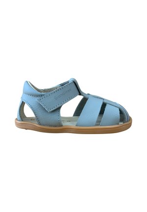 Sandalia azul claro para niño pequeño con puntera cerrada, tira ajustable con cierre de velcro y suela de goma color marrón claro, vista lateral sobre fondo blanco.