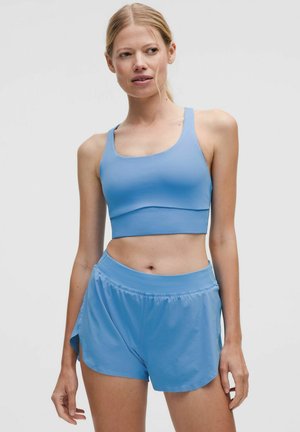 Sujetador deportivo de color azul claro combinado con pantalones cortos a juego. Ambos artículos presentan una textura suave y un diseño ajustado, ideal para ropa de actividad.