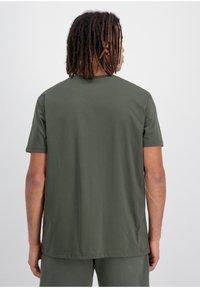 Zelené tričko s krátkým rukávem, kulatý výstřih, volný střih, vyrobené z měkké bavlněné tkaniny. Minimalistický design bez viditelných vzorů nebo akcentů.