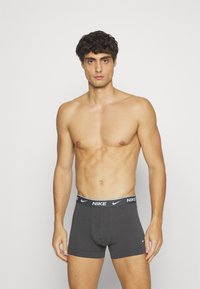 Szürke pamut boxeralsó, kontrasztos fekete derékrésszel, amelyen a Nike logo található. Simaság és testhezálló kialakítás jellemzi.