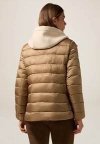 Padded beige jacket with horizontal seams and a cream hood. Smooth texture, regular fit, and subtle sheen. Plain design without embellishments.