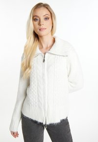 Maglione bianco con zip realizzato in un morbido tessuto testurizzato. Presenta un motivo a trecce, ampio colletto e polsini e orlo a costine.
