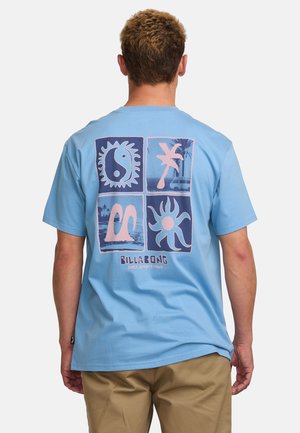 Lyseblå bomulds t-shirt med et grafisk print, der har fire firkantede designs, herunder sol- og bølgemotiver samt "Billabong" logoet.