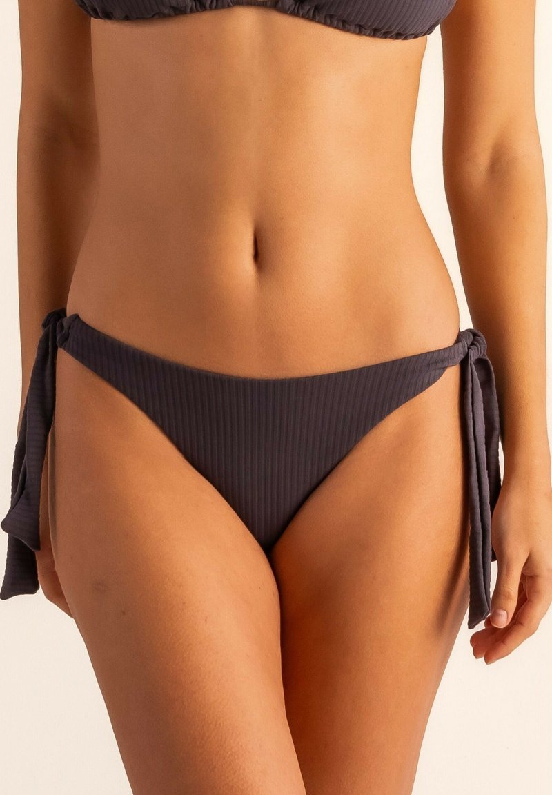 Bañador inferior de canalé gris oscuro con detalle de lazo en el costado, con un corte bajo y tejido texturizado para un diseño adicional.