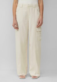 Lichtbeige cargobroek met een wijd model, voorzien van twee voorzakken en één zijzak, gemaakt van een lichtgewicht stof.