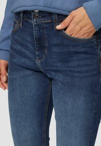 Donkerblauwe denim jeans met een slim fit, voorzien van zichtbare stiksels, een voorzak en een klassieke knoopsluiting.