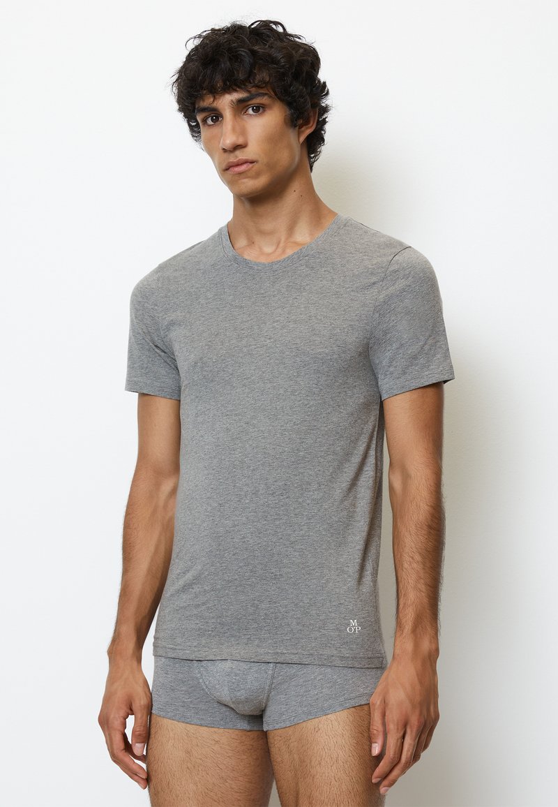 Szara bawełniana koszulka typu crew-neck z krótkim rękawem, w parze z dopasowanymi szarymi bawełnianymi majtkami, noszona przez modela na neutralnym tle.