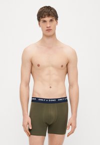 Oliwkowe bokserki wykonane z miękkiego materiału, z granatowym pasem w talii ozdobionym białym napisem "ONLY & SONS". Gładka tekstura i dopasowany krój.